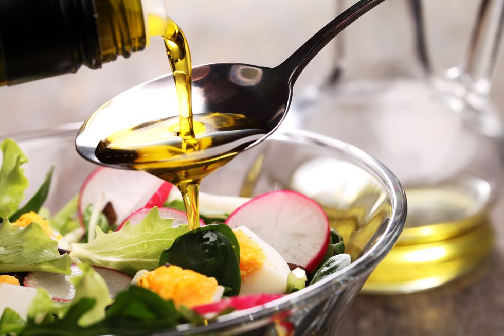 adding dressing to a salad in a glass bowl