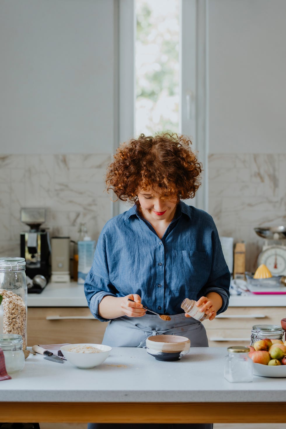 adding spices to the oatmeal beautiful woman putting cinnamon into a bowl with rolled oats