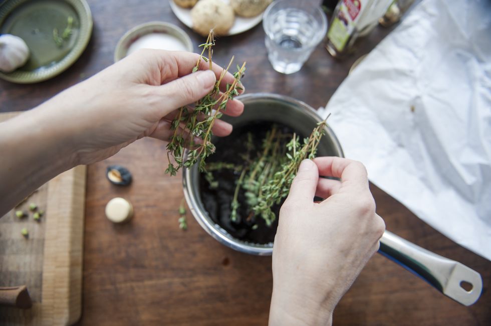 Adding thyme to a cooking pot