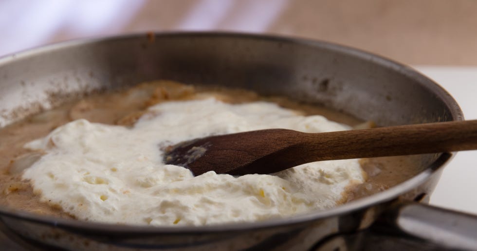 Adding whipped double cream to prepare onion sauce.