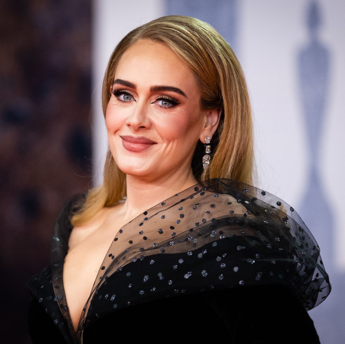 Adele con un look de otoño retro con gabardina de vinilo burdeos