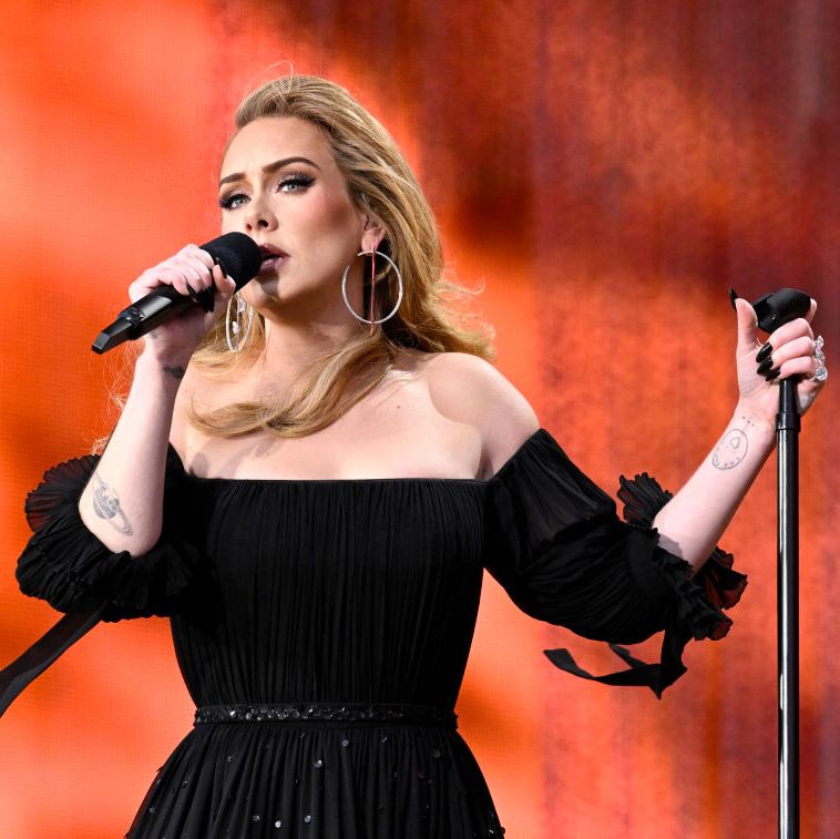 adele stands on stage singing in mic wearing a black dress