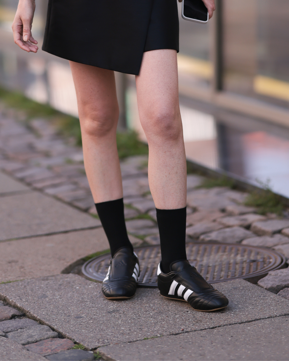 footwear featuring black and white sneakers paired with black socks set against a street background