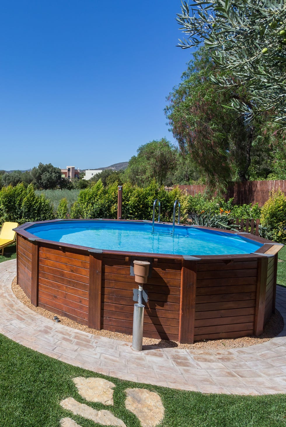 Above ground pool sets on a concrete pad . an above ground pool sets on a concrete pad in the backyard on a sunny summer day