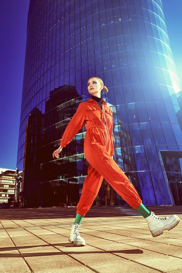 fashionable young woman in stylish colorful clothes poses in the business center of a big city urban style