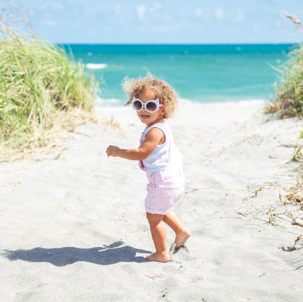adorable mixed race toddler headed to the ocean on an idyllic summer beach