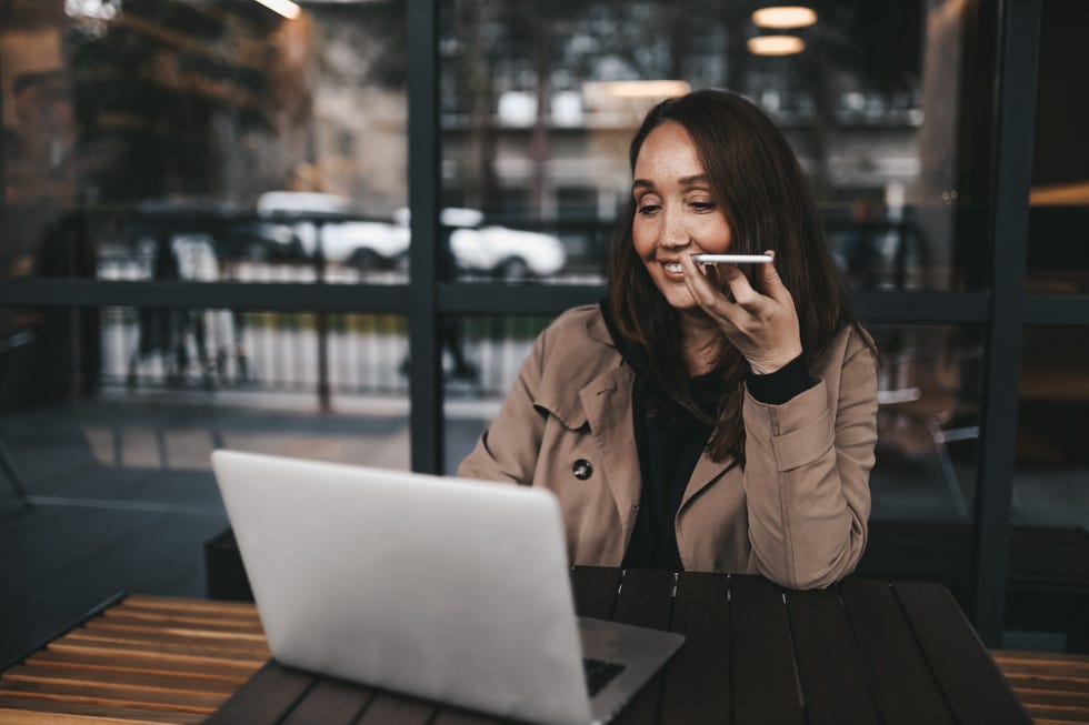 adult business woman freelancer works using wireless technology talking on the phone sitting in cafe