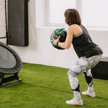 mujer entrenando con un balón medicinal en el gimnasio