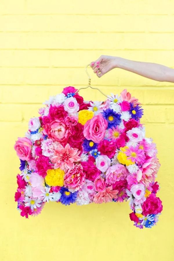 adult craft ideas, hand holding a faux flower coat in front of yellow wall outdoors