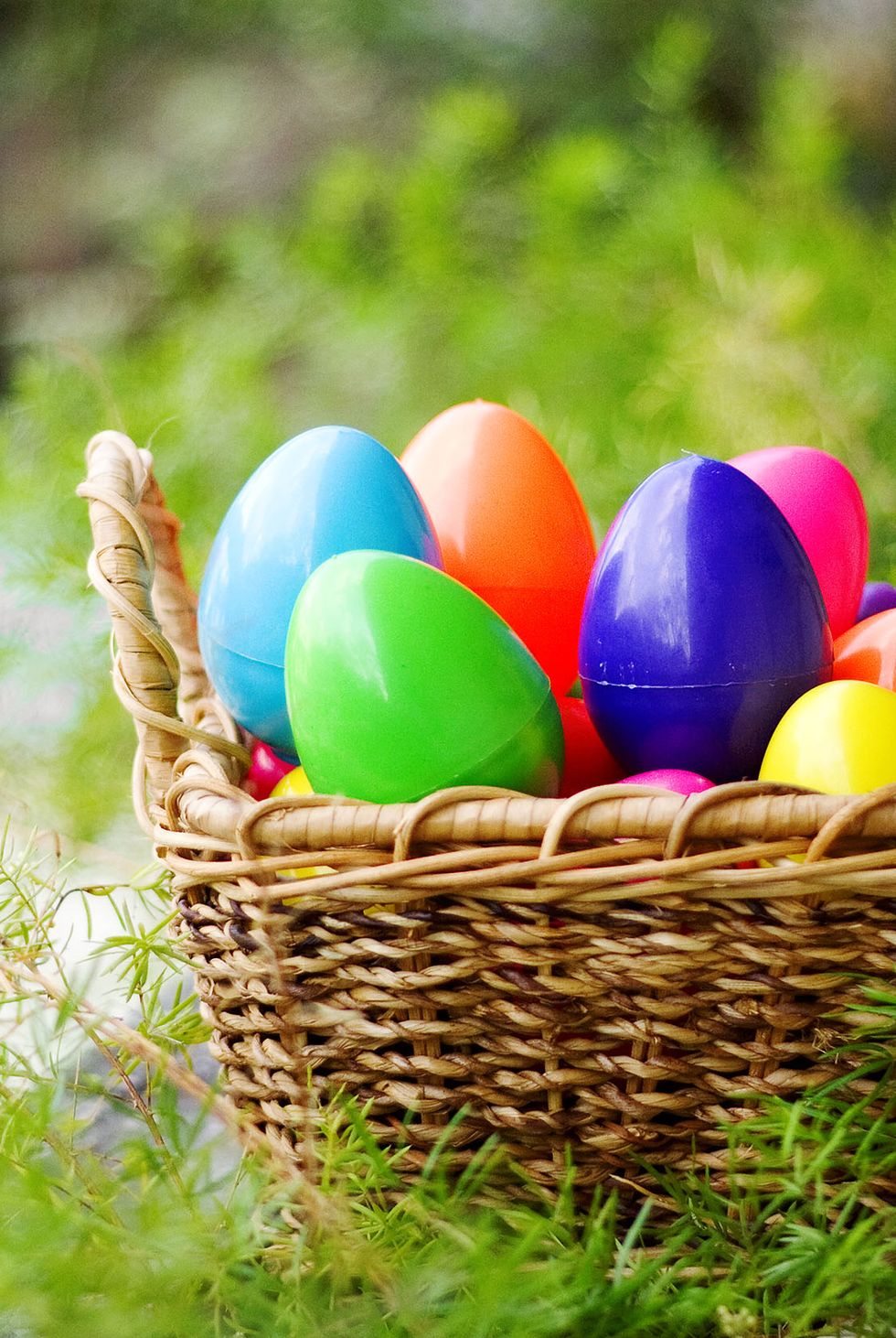 woven basket nestled in grass, brimming with colorful plastic eggs filled with recipes for an easter egg hunt idea for adults