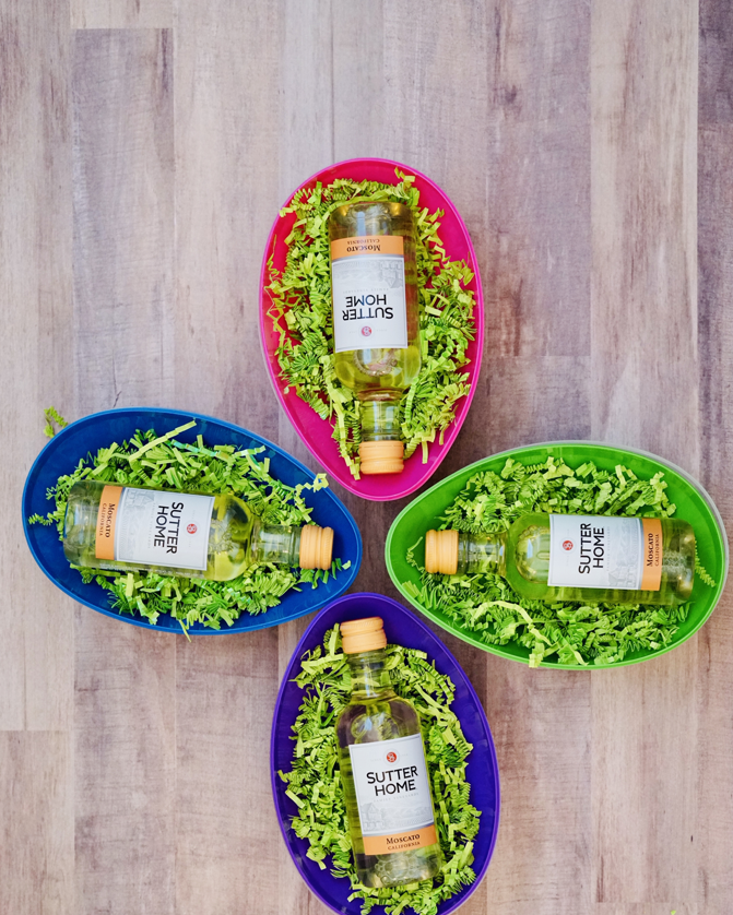 boozy adult easter egg hunt idea with colorful jumbo plastic eggs filled with green paper shreds and mini sutter home bottles