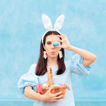 woman wearing bunny ears holding easter basket of eggs
