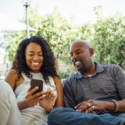 adult siblings looking at smart phone together in backyard