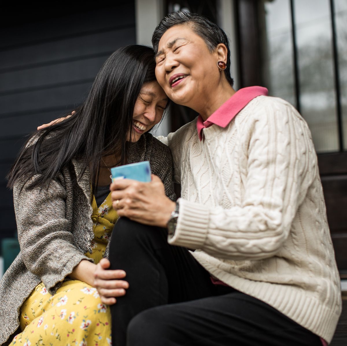 adult woman and senior mother talking on front porch