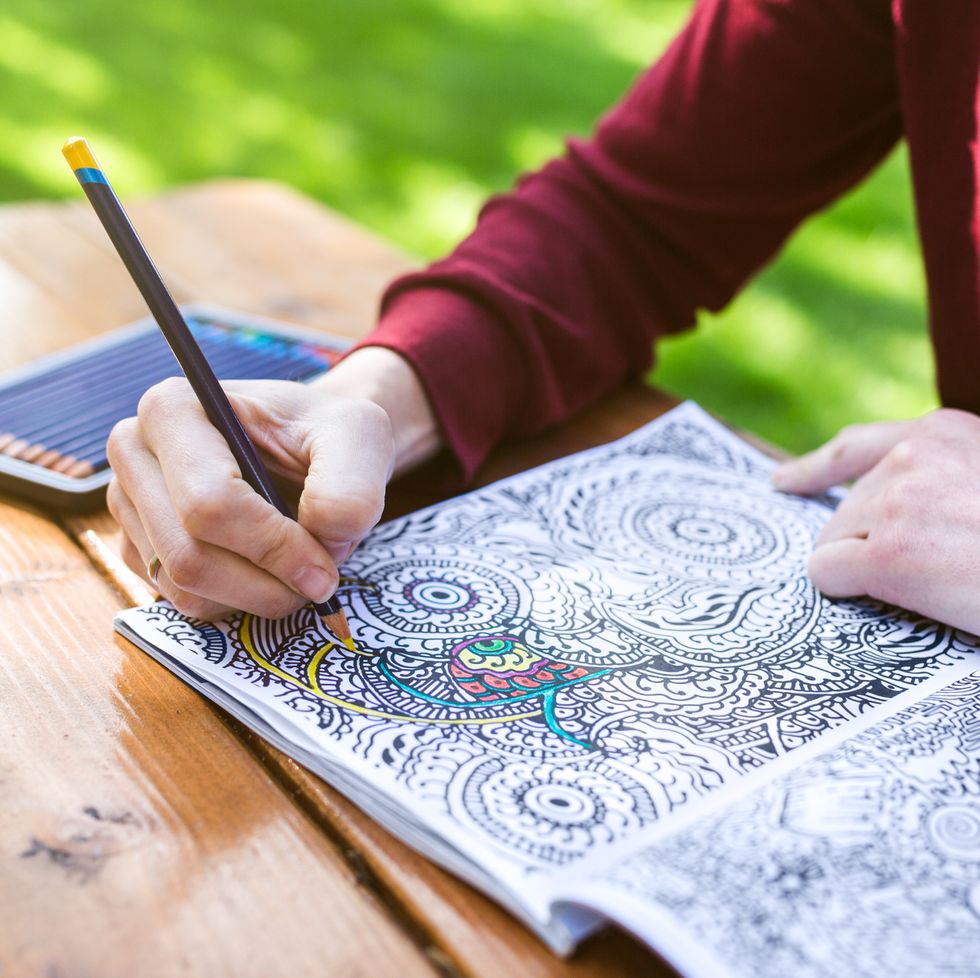 close on hands of adult woman coloring