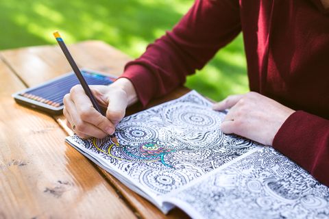 close on hands of adult woman coloring