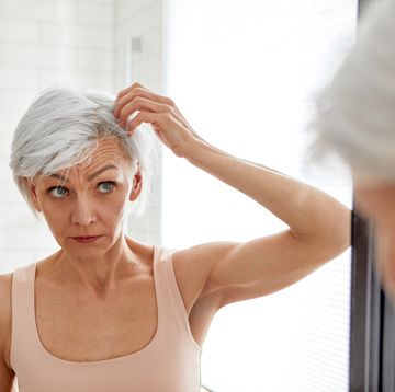 adult woman looking at her gray hair in the mirror