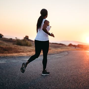 adult woman waterproof running on road at sunset