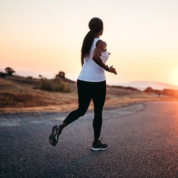 adult woman running The on road at sunset