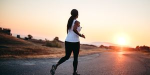 adult woman flat running on road at sunset