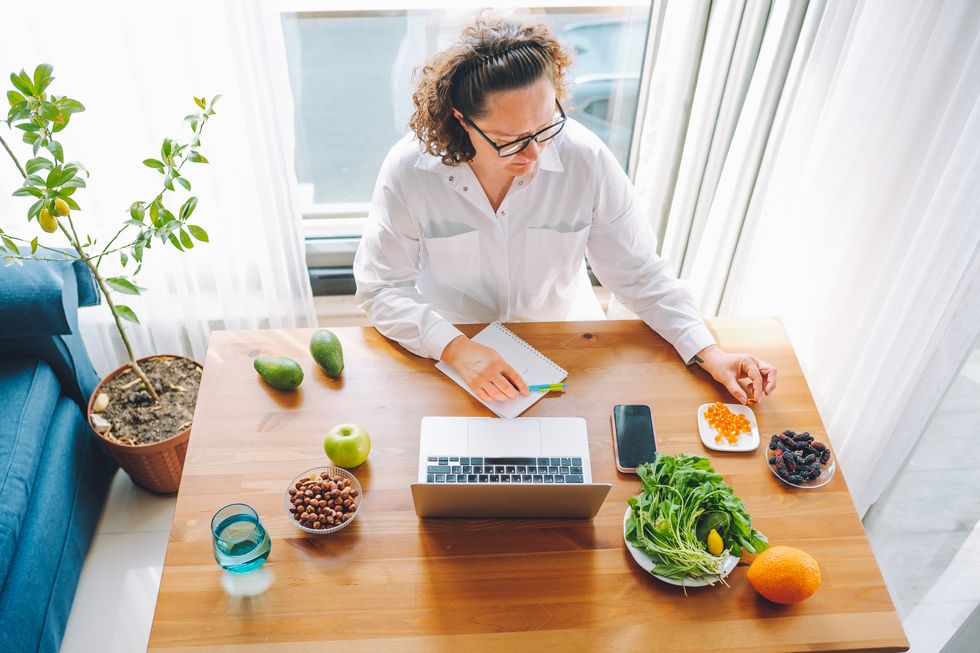 advanced training courses for nutritionist online female doctor picking yellow pills from the plate, handwriting notes and work on a laptop in light office