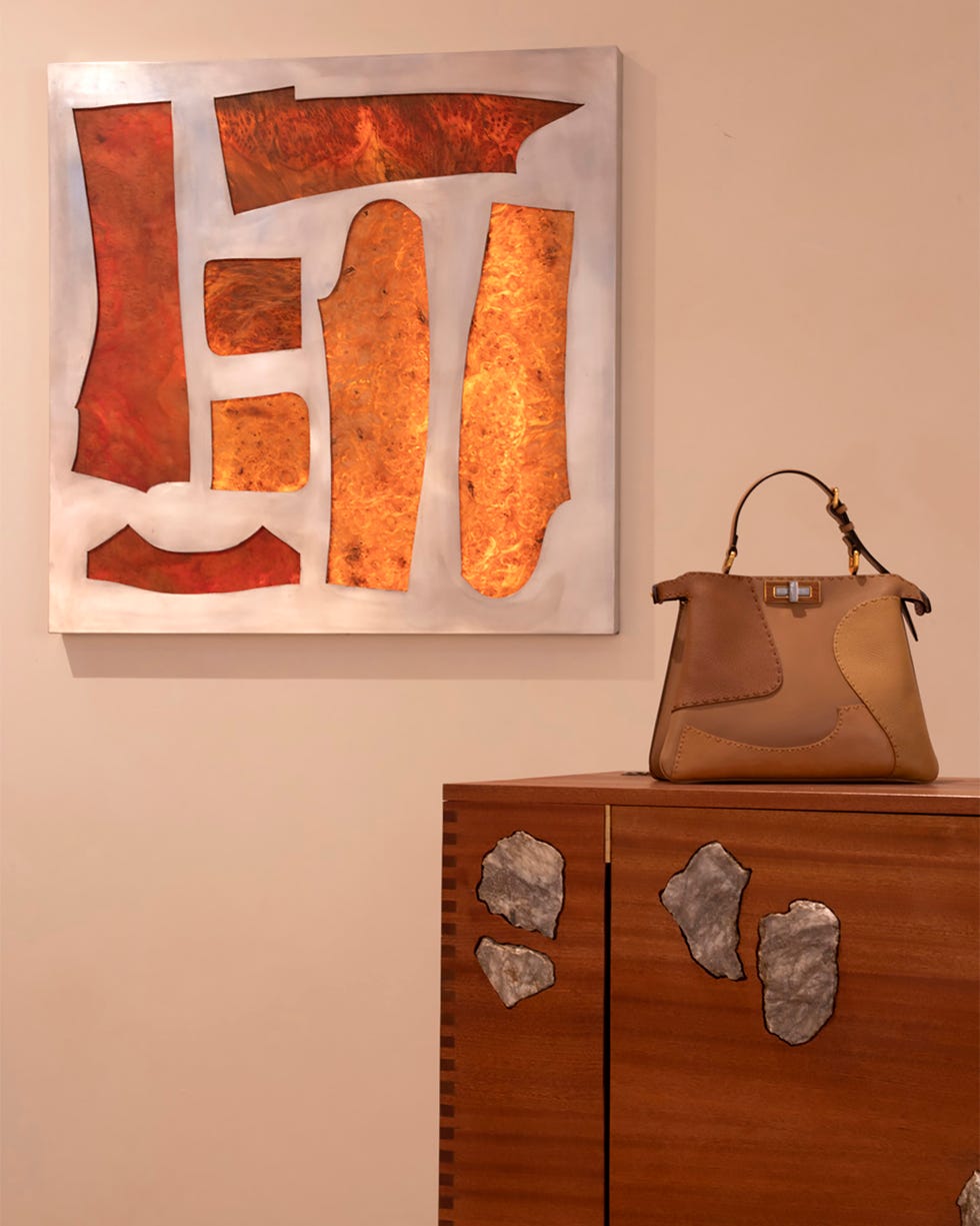 contemporary art piece next to a designer handbag on a wooden chest