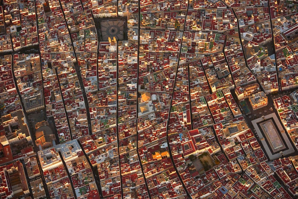 De stad Cdiz in Spanje is van boven gezien net zo fascinerend als op straatniveau mooie straten nauwe steegjes prachtige architectuur leuke markten en mensen en geweldige kerken Het heeft het echt allemaal Ga er eens naartoe en dwaal er gewoon wat rond  Deze foto werd genomen vanuit een vliegtuig tijdens het gouden uur