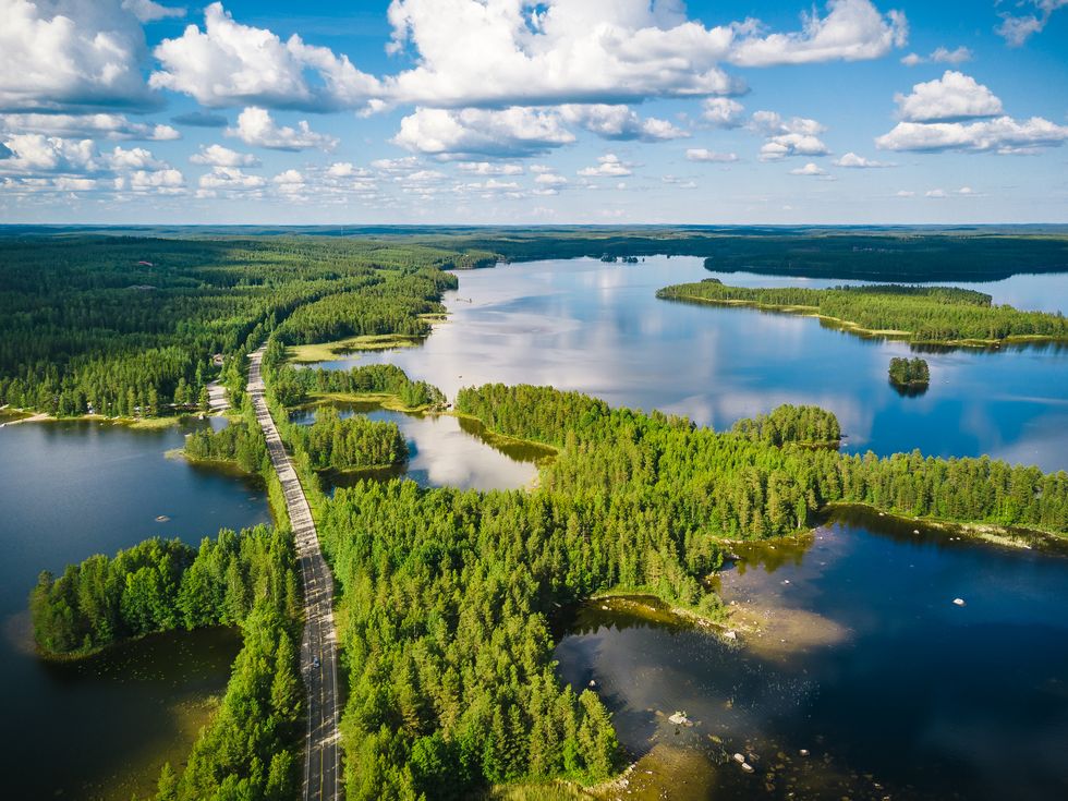 aerial view of a winding road passing through forests lakes in finland on a summer day