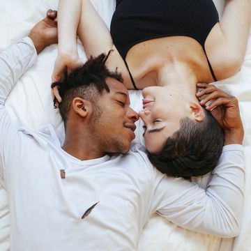 aerial view of interracial couple of lovers lying on a white bed on a romantic weekend