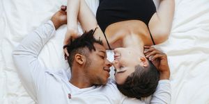 aerial view of interracial couple of lovers lying on a white bed on a romantic weekend