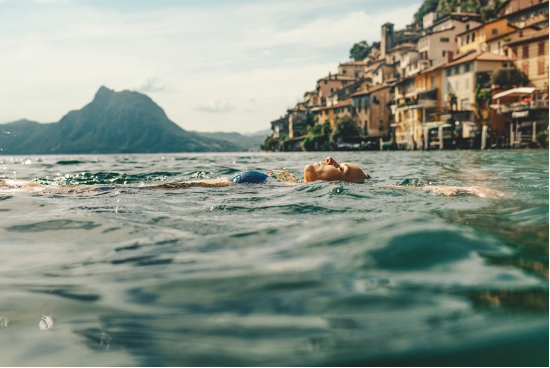 Een zwemster in het Meer van Lugano vanwaar je een prachtig uitzicht hebt op de stad