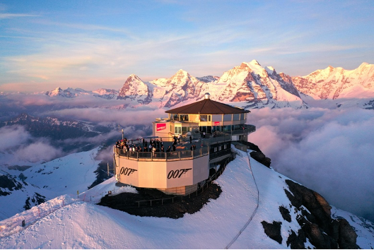 Het restaurant Piz Gloria op de Schilthorn tijdens zonsondergang met Eiger Mnch en Jungfrau op de achtergrond