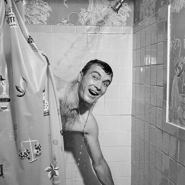 1950s man in shower turning on water and pulling shower curtain closed photo by debrockeclassicstockgetty images