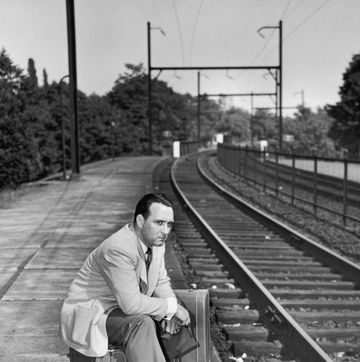 a grumpy looking man sits on his suitcases as he waits for a train, circa 1954 photo by lamberthulton archivegetty images