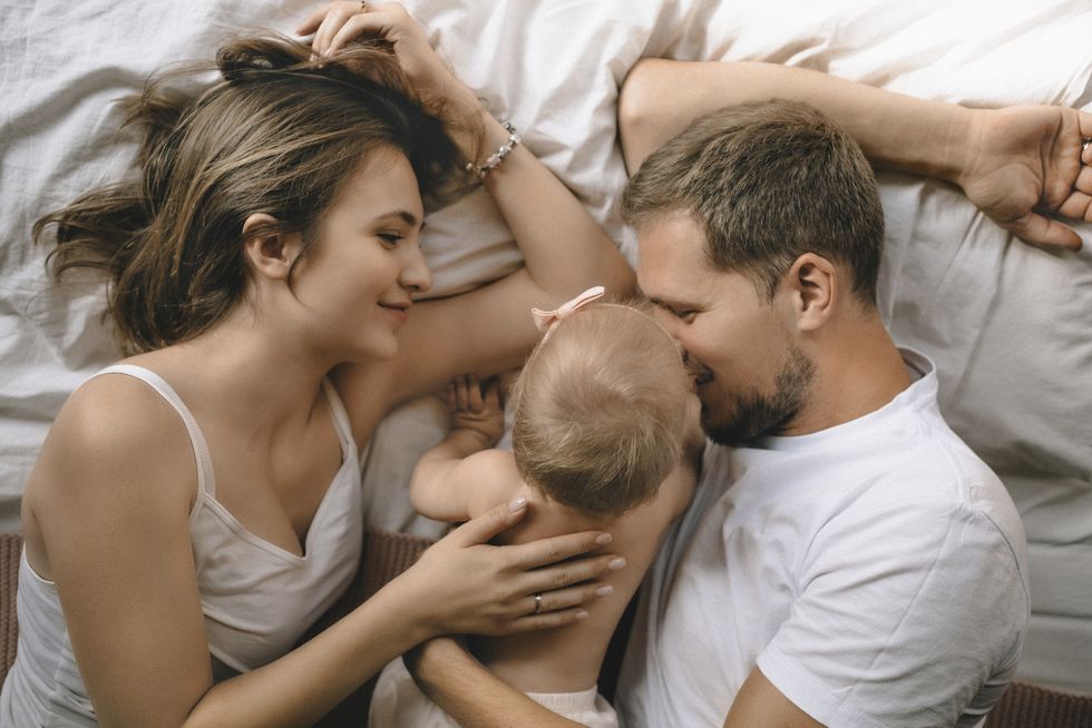 affectionate father, mother and baby girl lying in bed