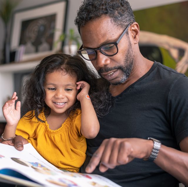 affectionate father reading book with adorable mixed race daughter