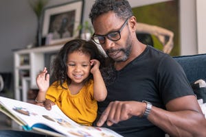 affectionate father reading book with adorable mixed race daughter