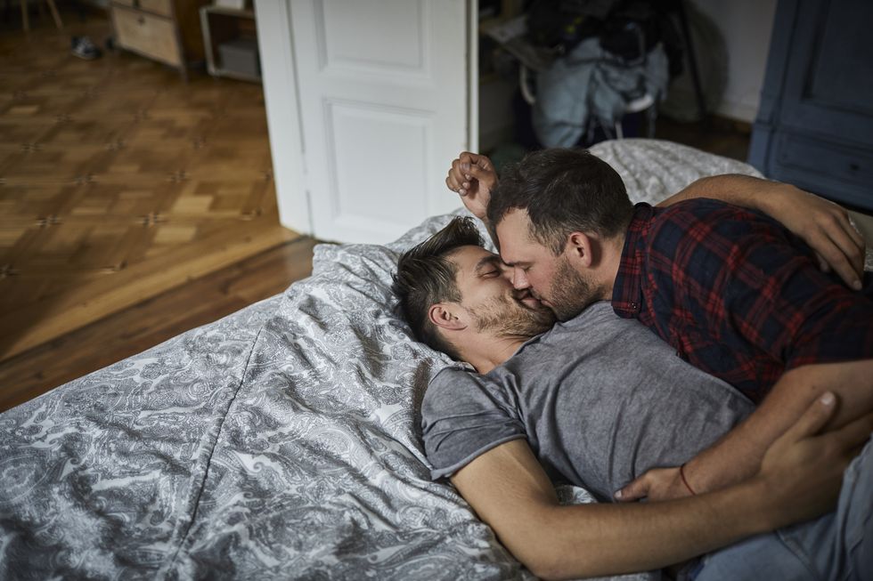 affectionate gay couple kissing in bed at home