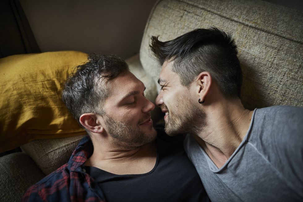 Affectionate gay couple resting on couch at home