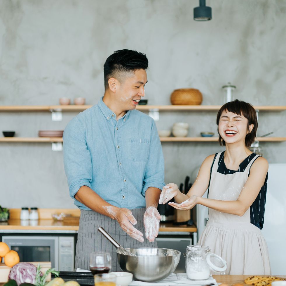 affectionate young asian couple having fun while baking together in a domestic kitchen