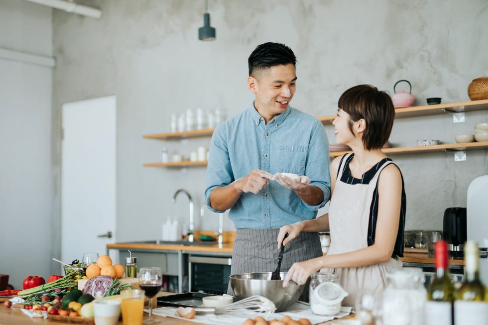 affectionate young asian couple preparing cookies together in a domestic kitchen