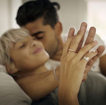 affectionate young man kissing woman while holding hand in bedroom