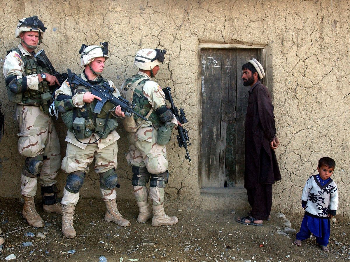 afganistan   november 7  an afghan man and his son watch as soldiers from the us army 82nd airborne division prepare to sweep their home november 7, 2002 in southeastern afghanistan soldiers discovered over a dozen mines and grenades, 14 rocket propelled grenades, and plastic explosives as they searched several compounds as part of operation alamo sweep photo by scott nelsongetty images