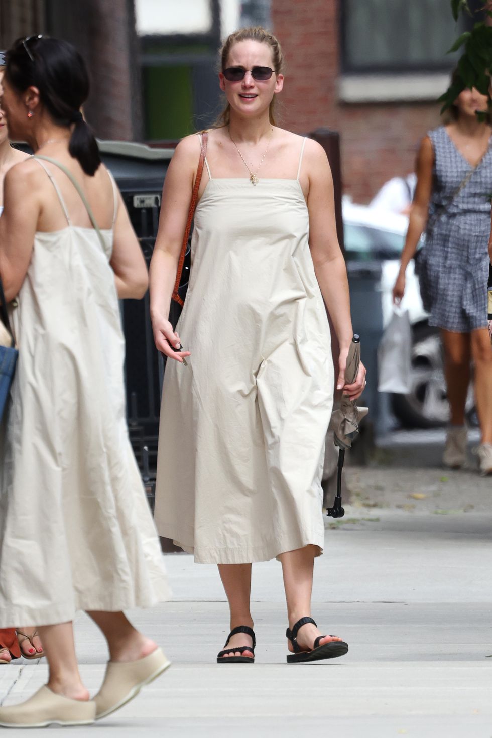 07312022 exclusive jennifer lawrence is pictured admiring a woman who is wearing the same dress as herself in new york city the american actress carried a black leather bag and wore a yellow sundress, and black sandalssalestheimagedirectcom please bylinetheimagedirectcomexclusive please email salestheimagedirectcom for fees before use