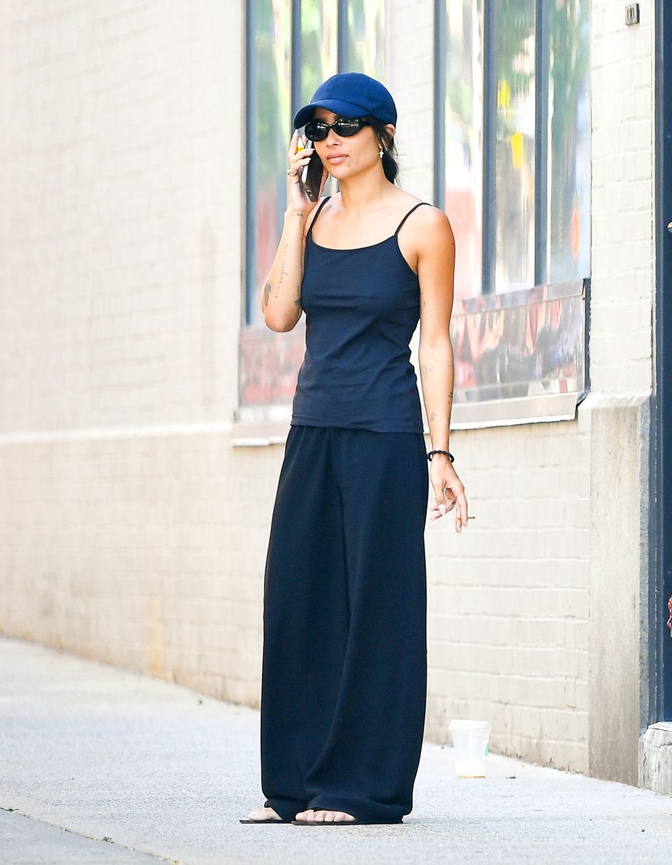 08242022 exclusive zoe kravitz is spotted taking a smoke break in new york city the 33 year old actress wore a baseball cap, dark blue tank top, black trousers, and sandals salestheimagedirectcom please bylinetheimagedirectcomexclusive please email salestheimagedirectcom for fees before use