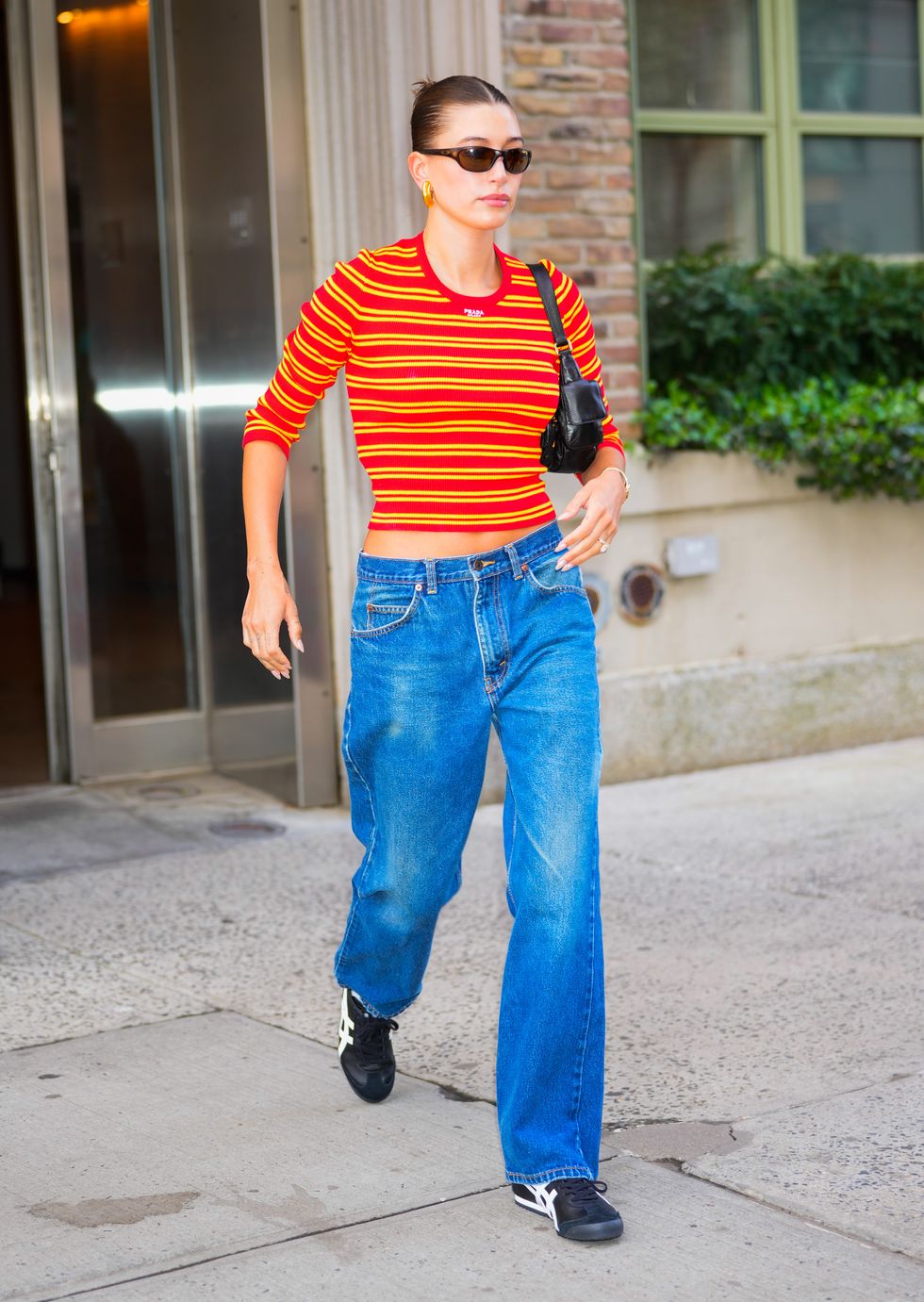 04112023 exclusive hailey bieber is pictured stepping out in new york city the american supermodel wore a bright orange prada crop top, blue jeans, and asics sneakers salestheimagedirectcom please bylinetheimagedirectcomexclusive please email salestheimagedirectcom for fees before use