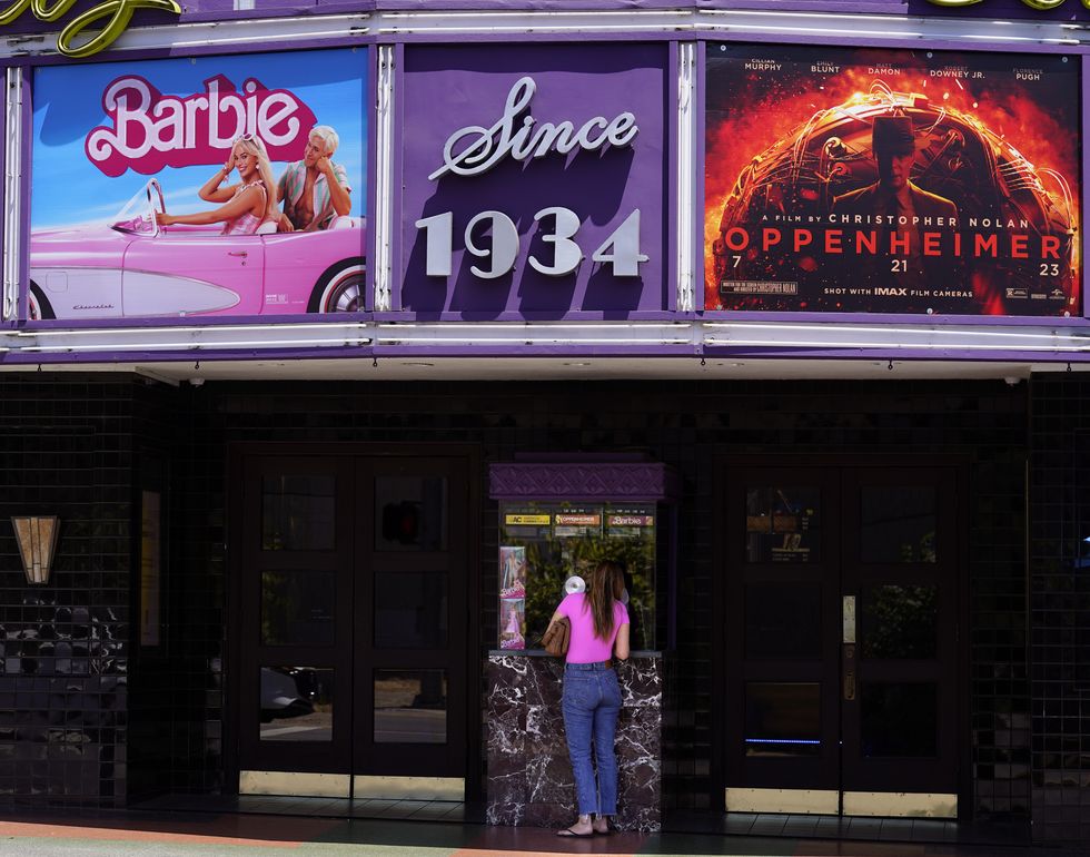 a patron buys a movie ticket underneath a marquee featuring the films barbie and oppenheimer at the los feliz theatre, friday, july 28, 2023, in los angeles ap photochris pizzello