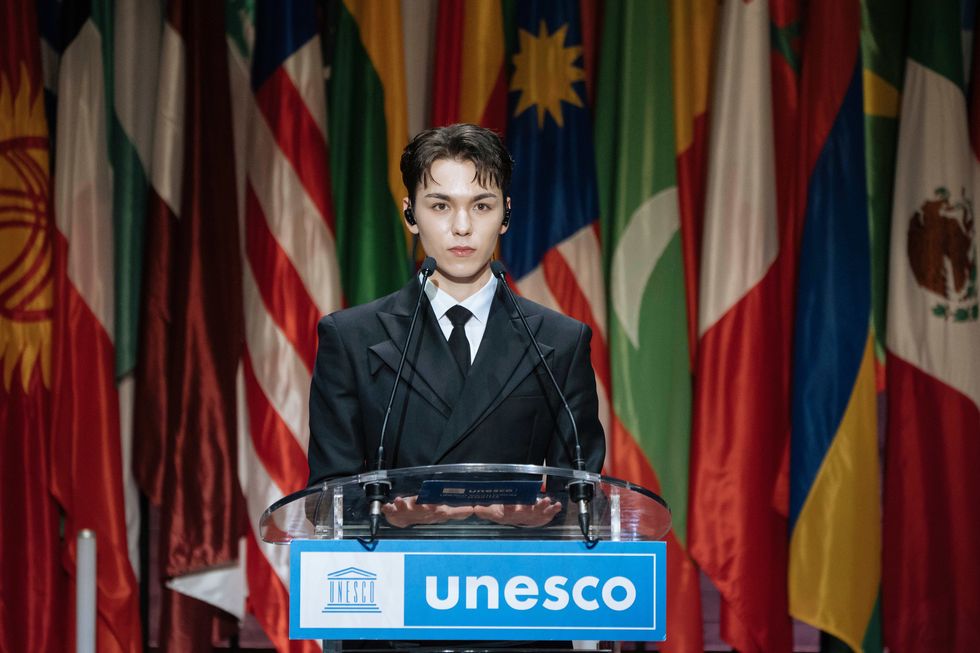 a person standing at a podium with a microphone in front of flags