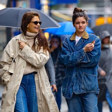 a couple of women walking down a sidewalk with umbrellas