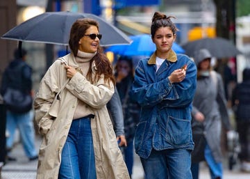 a couple of women walking down a sidewalk with umbrellas